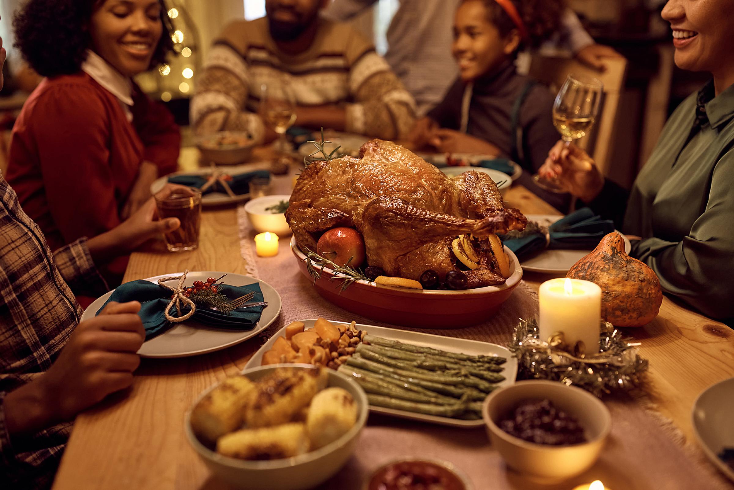 Large family gathered around a table with a turkey and several side dishes