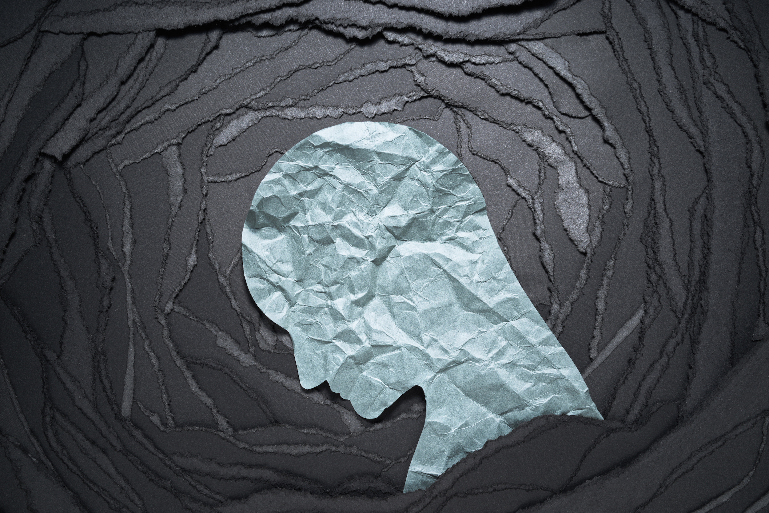 Paper cutout of a man's head on a black background.