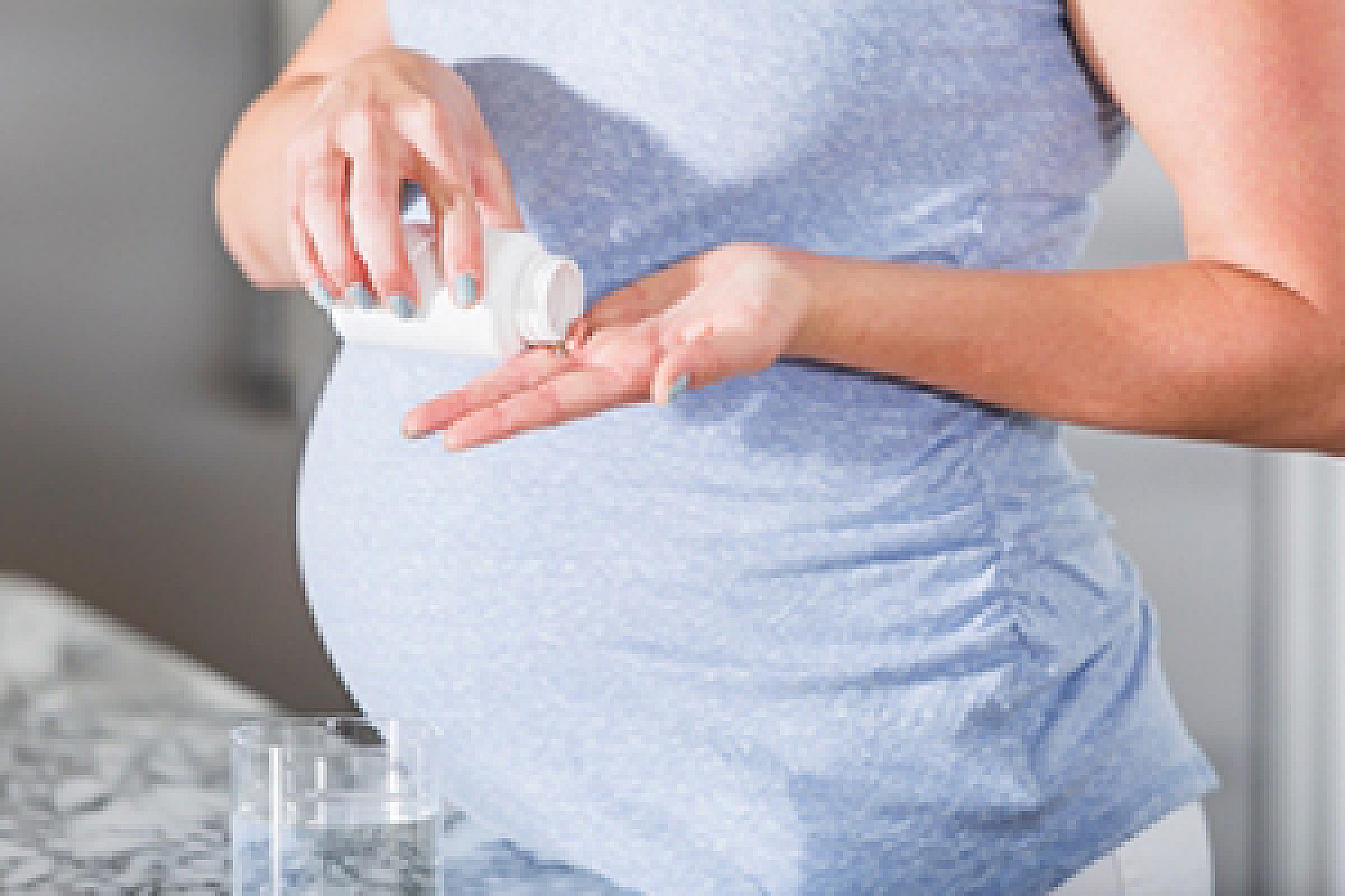 Pregnant woman pouring pills out of bottle
