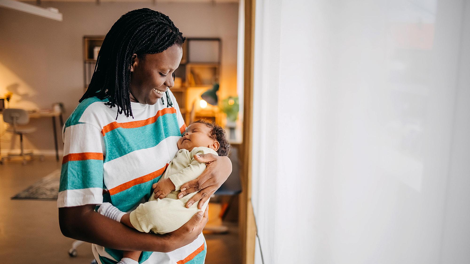 Smiling Black mother holds newborn baby