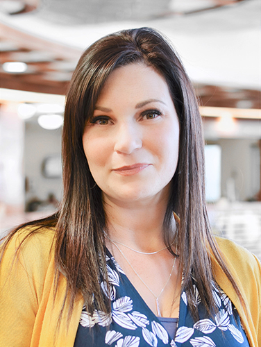 Woman named A'Lisha Finch with brown hair smiling wearing a blue shirt with yellow cardigan