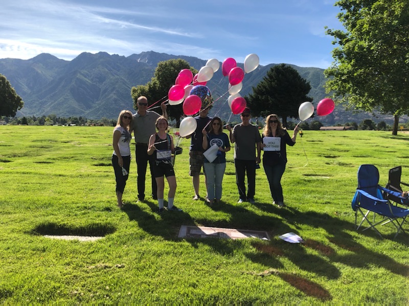 group of people standing in cemetery holding signs and balloons