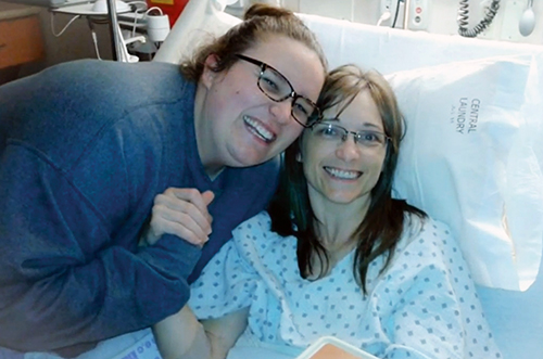Kiera leaning down to hug her mom who is in a hospital bed