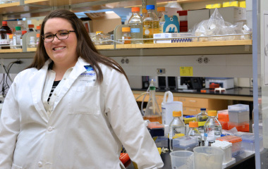 Kiera Jorgensen wears a lab coat in her undergraduate research lab
