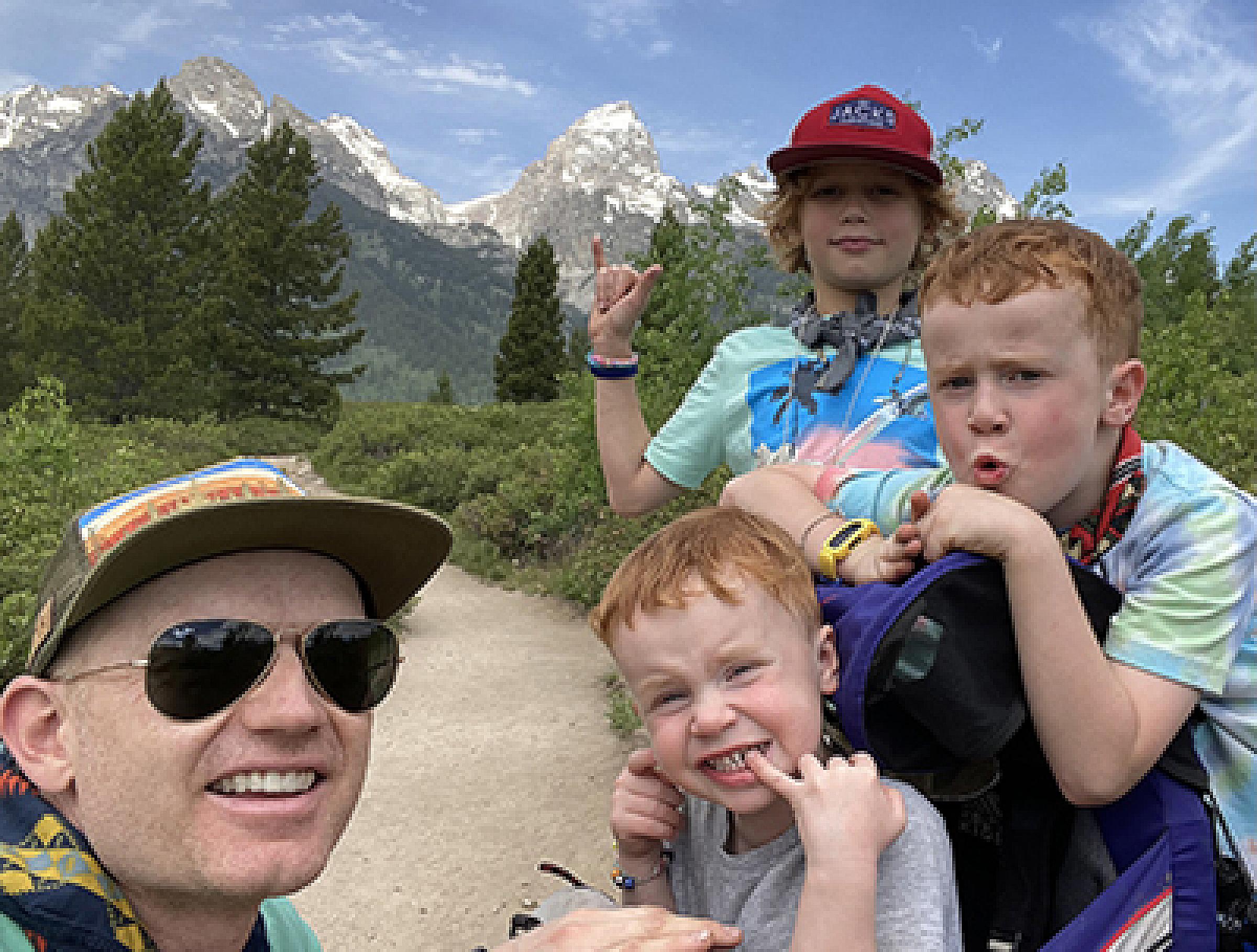 Brandon Plewe and three of his sons posing for a picture on a hiking trail in the mountains