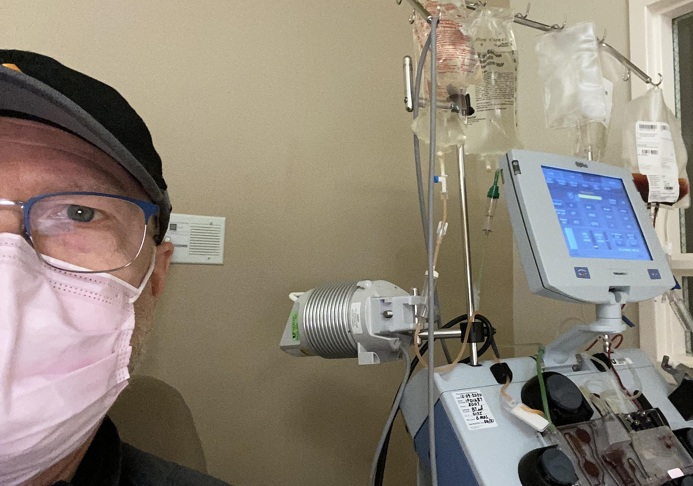 Bret Boyle sitting next to an infusion machine prior to CAR T therpay