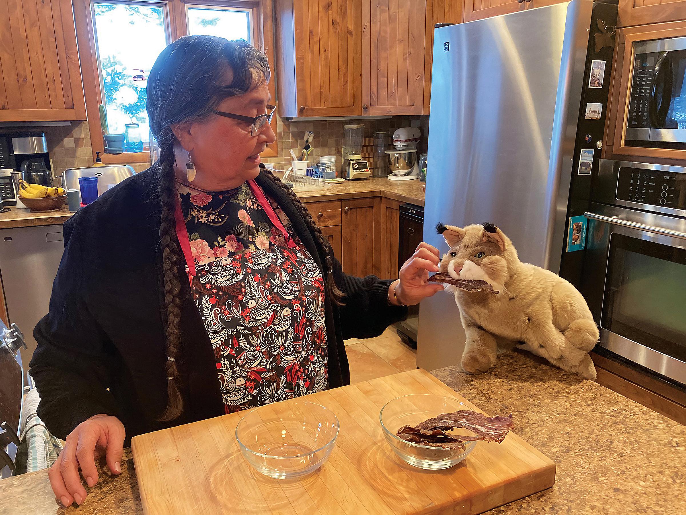Igmu, the Turtle Island Tales mascot, tries dry meat in a video about how to make traditional First Nations foods, part of the CAIRHE 2gether program wellness kit.