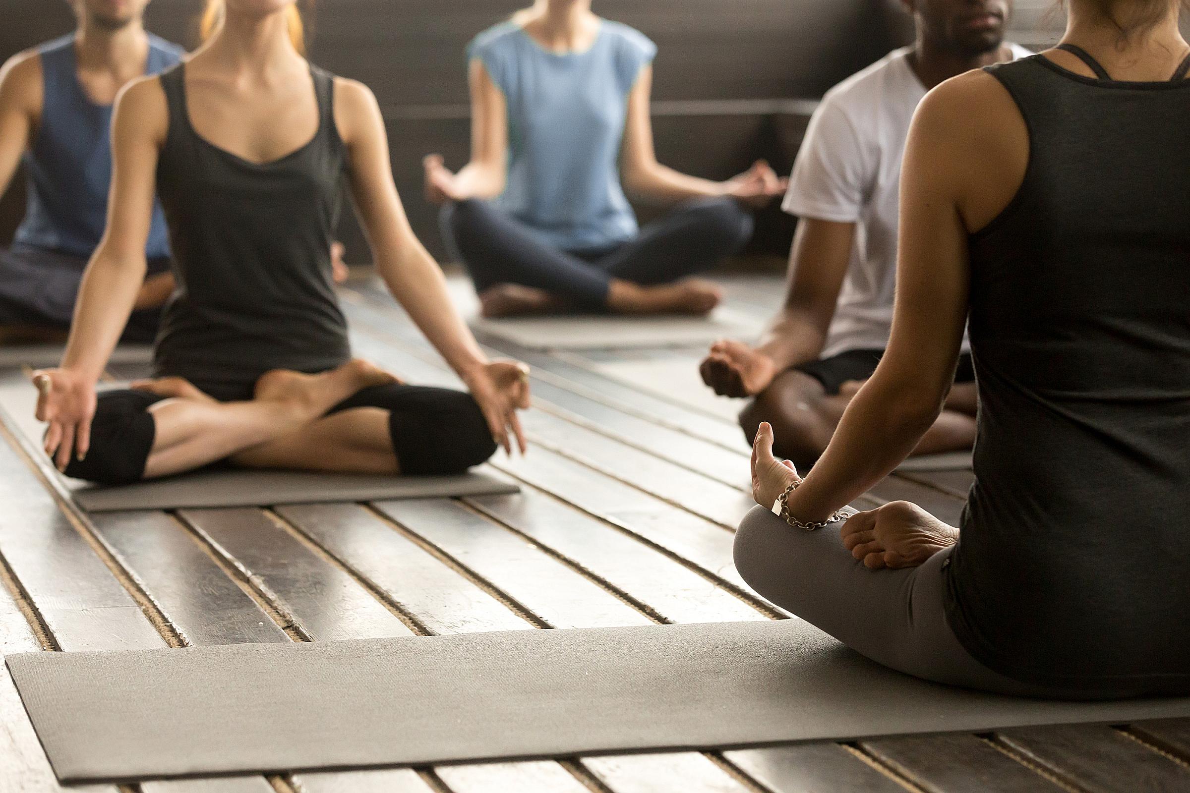 Group of people sitting on yoga mats in a studio