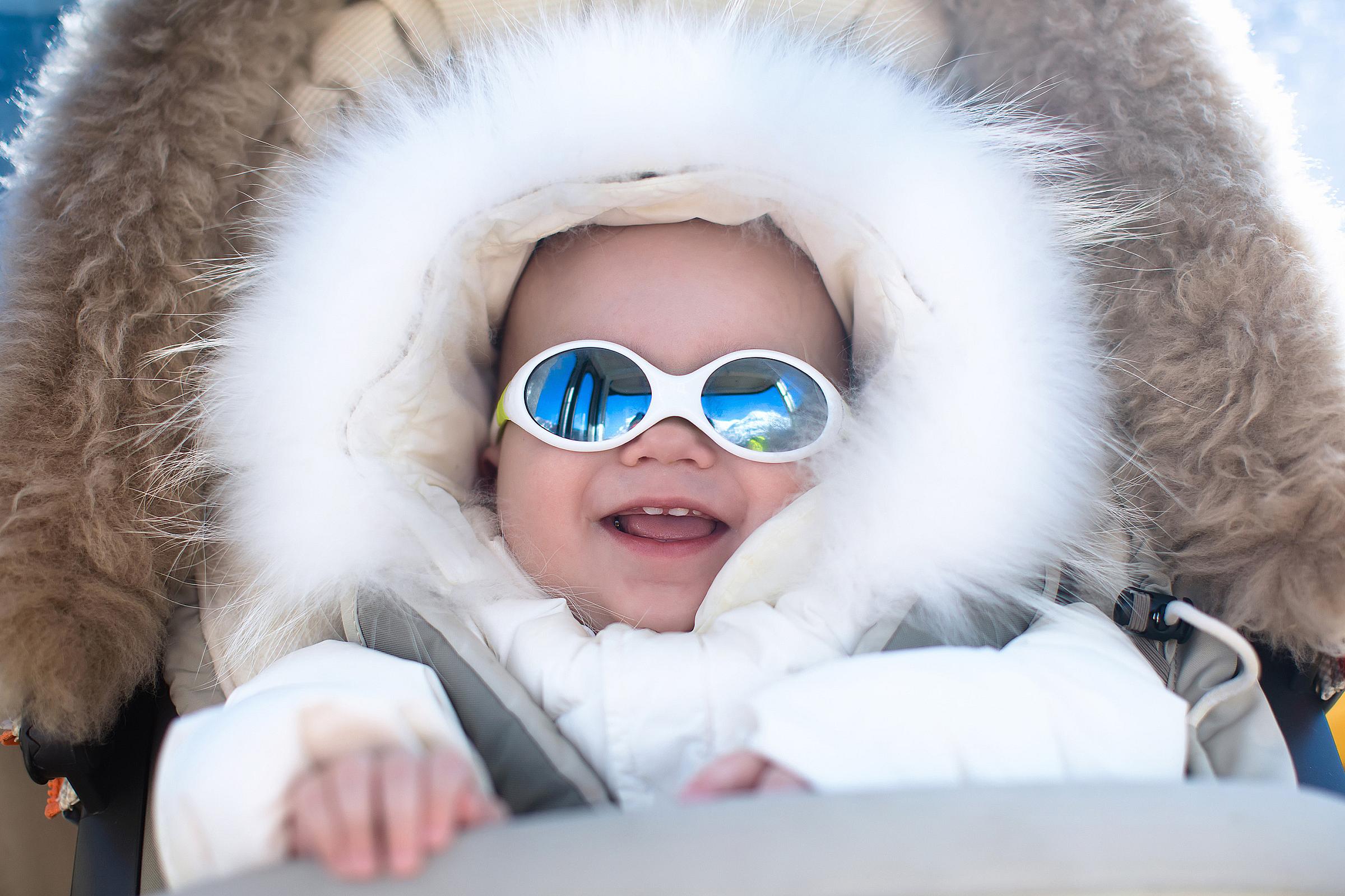 Baby in a snowsuit wearing sunglasses