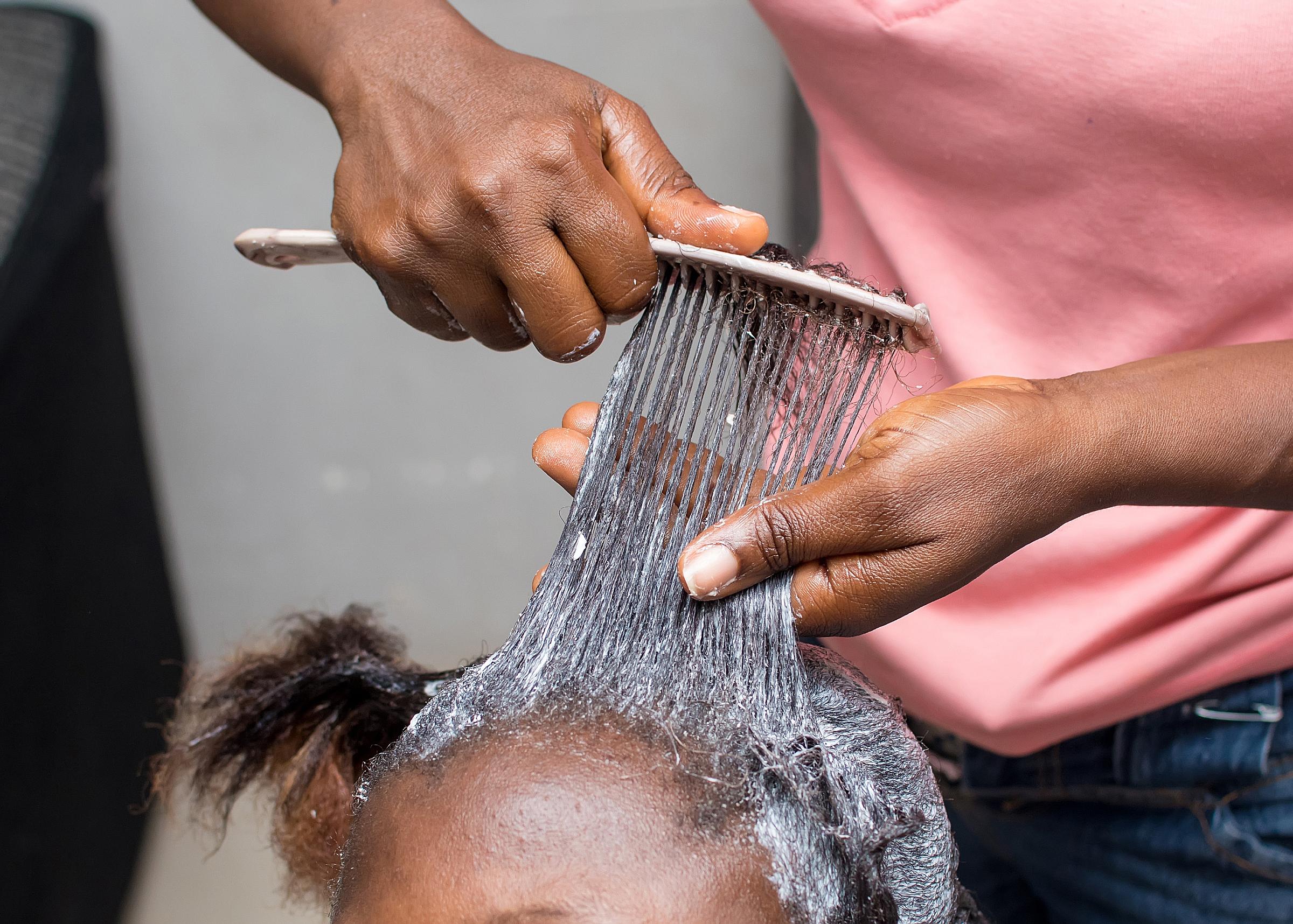 little black girl getting her hair straightened with chemicals