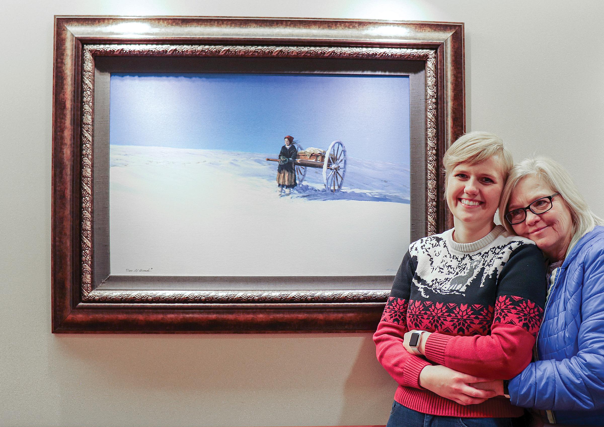 Emma Wageman (left) and her mother standing in front of "Trial of Hope...Last Hill" by artist Al Rounds, located on the fourth floor of the cancer hospital.