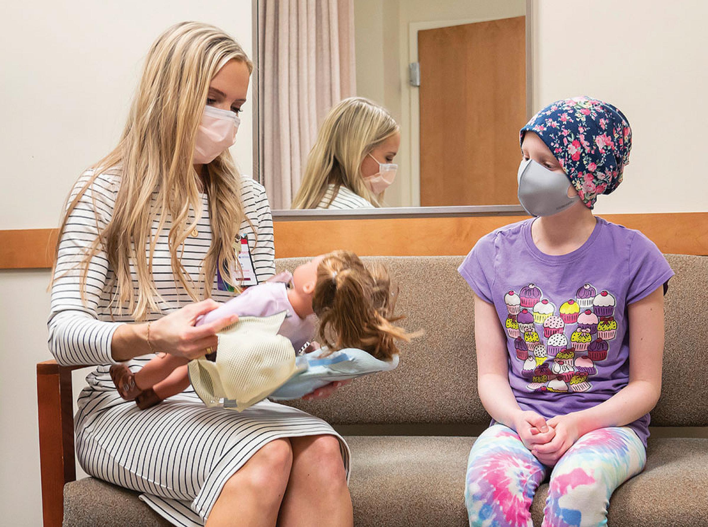 Huntsman Cancer Institute child life specialist Abbie Lofgren talks to Emma Bresee before one of her appointments.