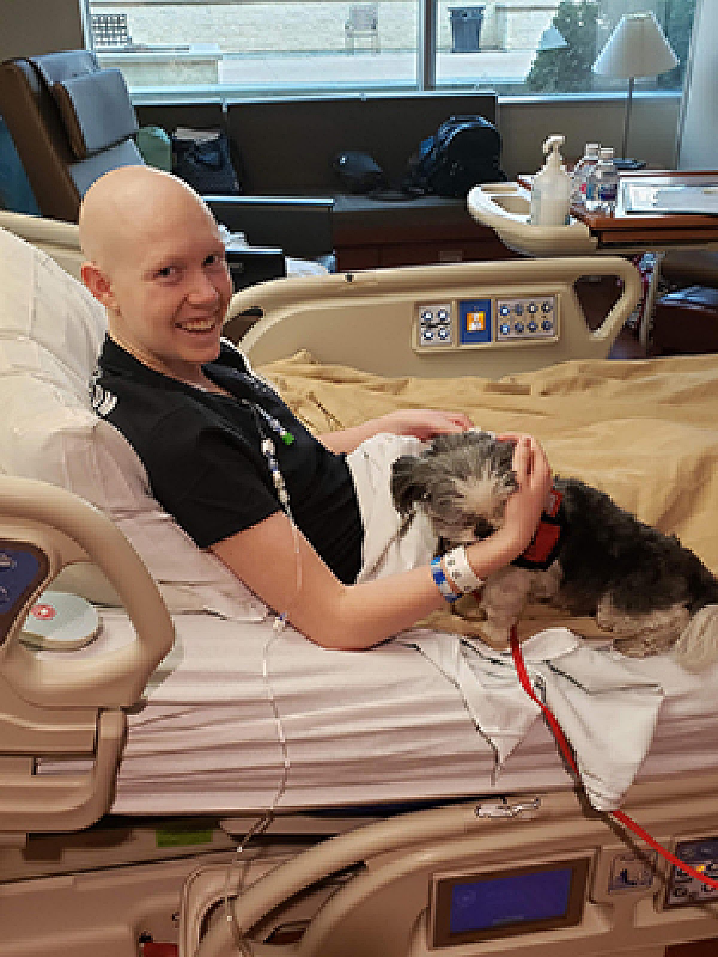 Erin Hurst sitting in hospital bed with a dog on her lap