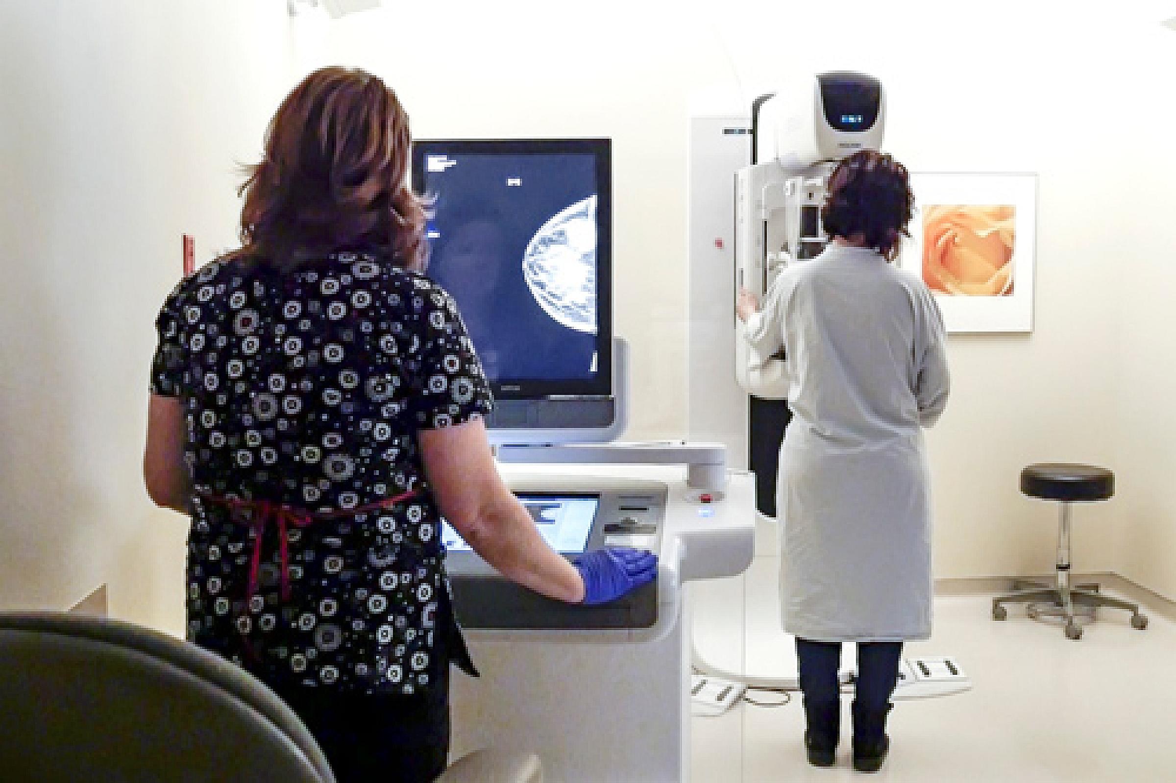 Mammogram scene with tech reviewing image and patient in the machine