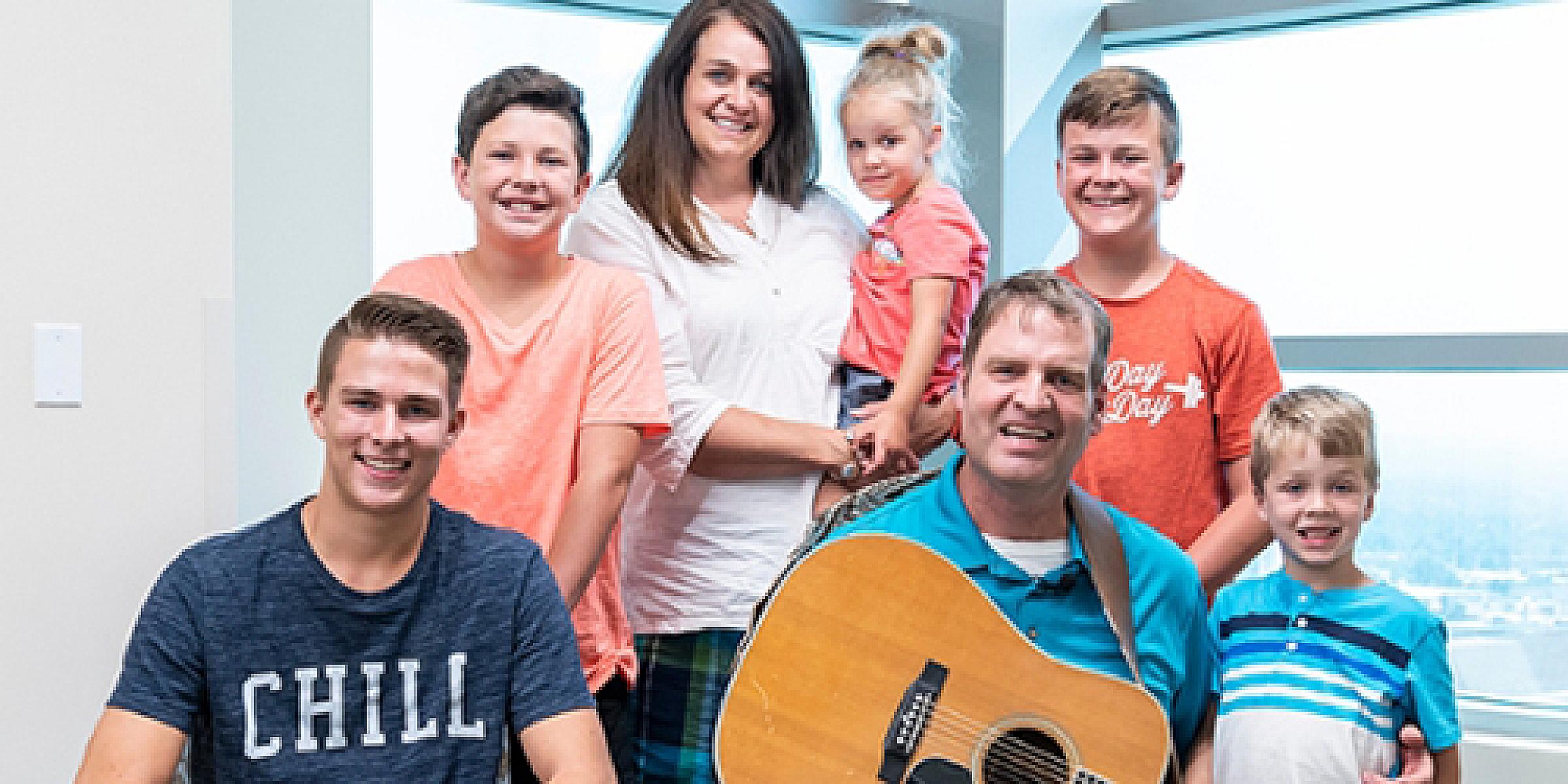 Matt Pond holding a guitar with his family