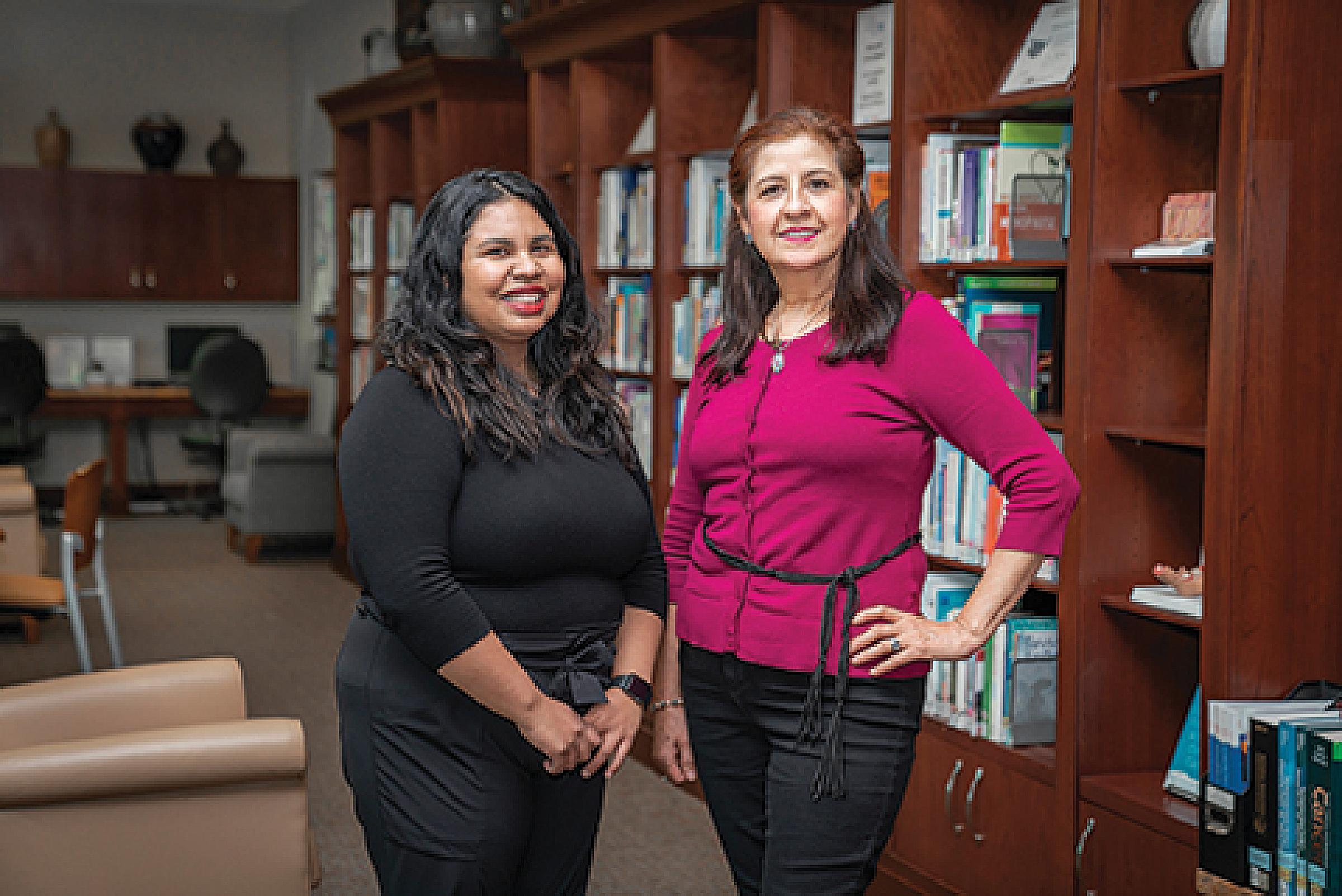 Anna Martinez and Guadalupe Tovar standing next to bookshelf