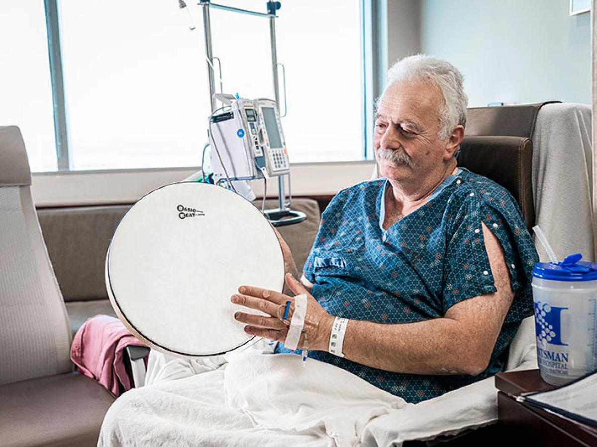 Patient taps drum as part of music therapy
