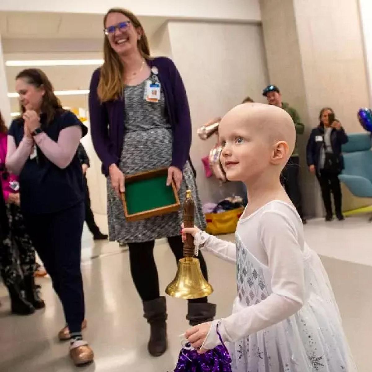 Parker holding a bell to celebrate completing her chemotherapy treatment