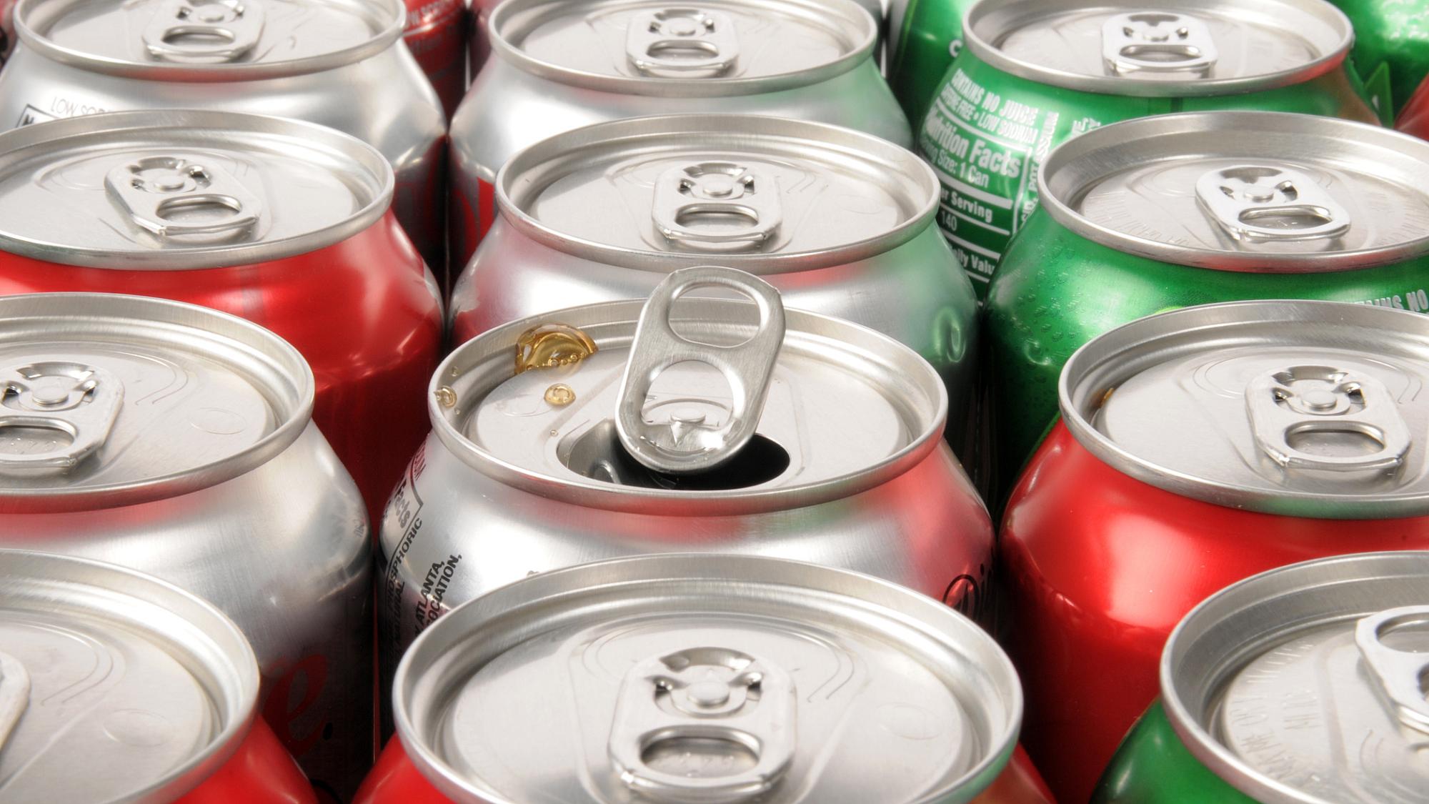 Rows of different colored cans of soda and one has been opened