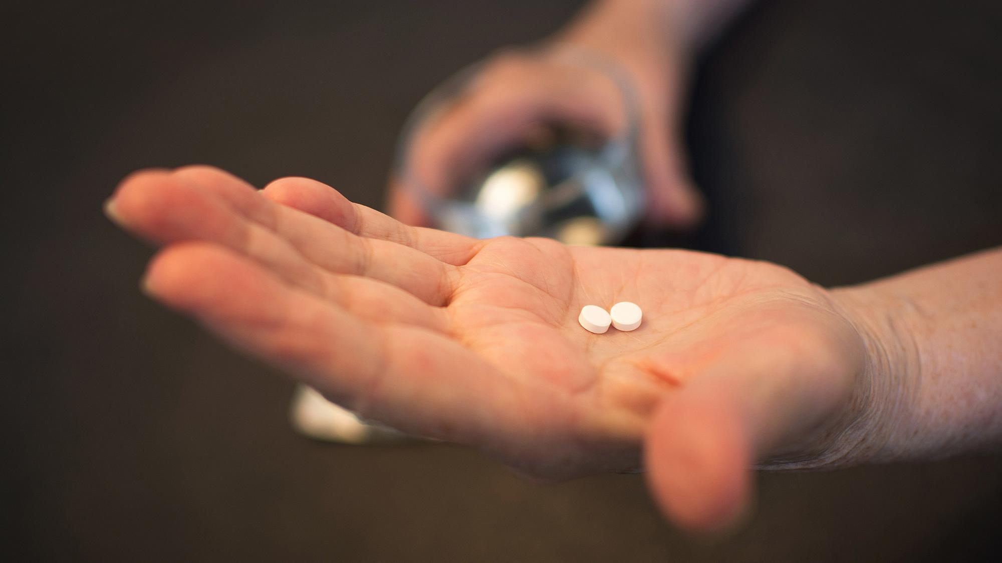 Hand holding two white pills