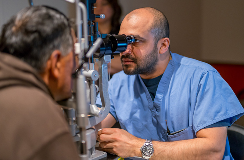 Moran retinal specialist Akbar Shakoor, MD, examines a patient during the Hope in Sight Refugee Clinic in 2017.
