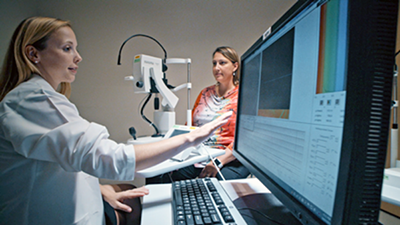 Lydia Sauer, MD, left, examines a patient using fluorescence lifetime imaging ophthalmoscopy (FLIO).