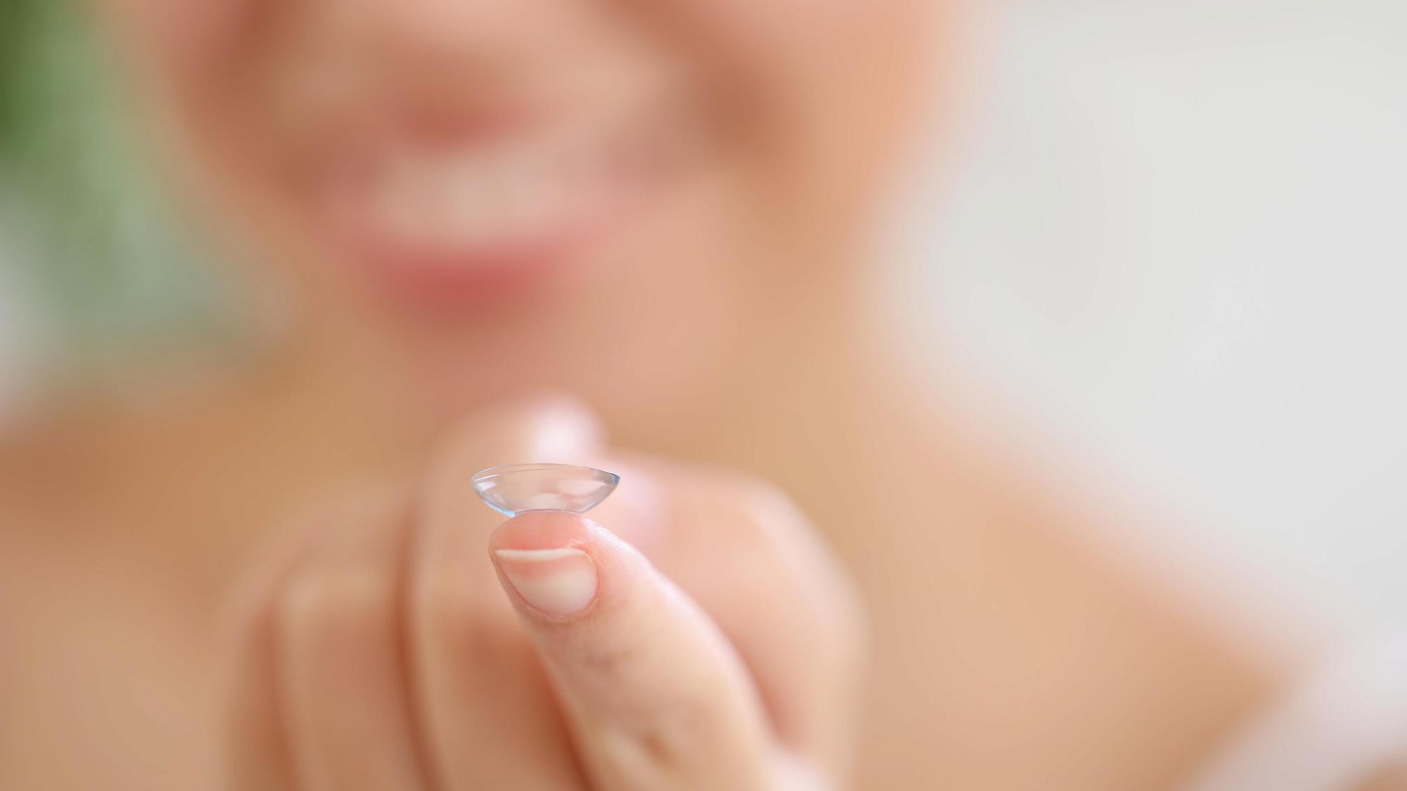 Woman holding a contact lens.