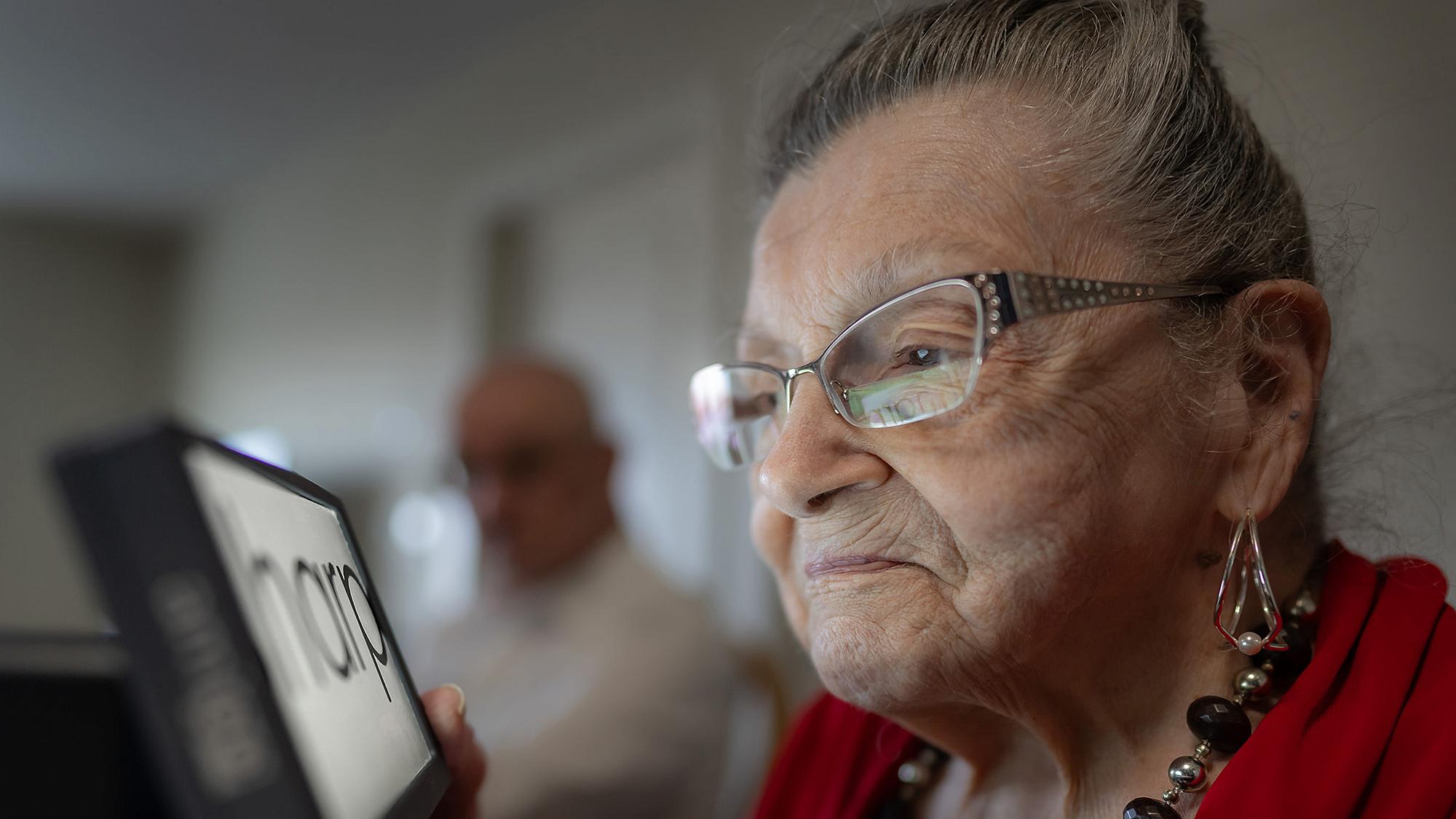 A patient reads with a magnifier device supplied by the Patient Support Program.
