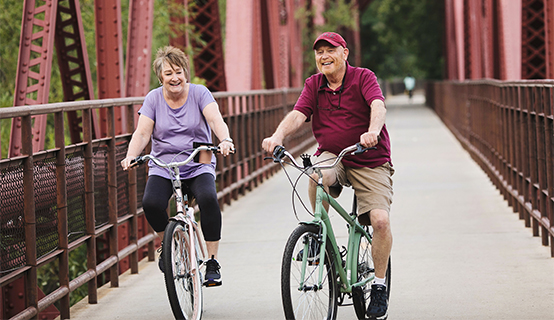 Picture of Dan Owens riding his bike over a bridge with his wife