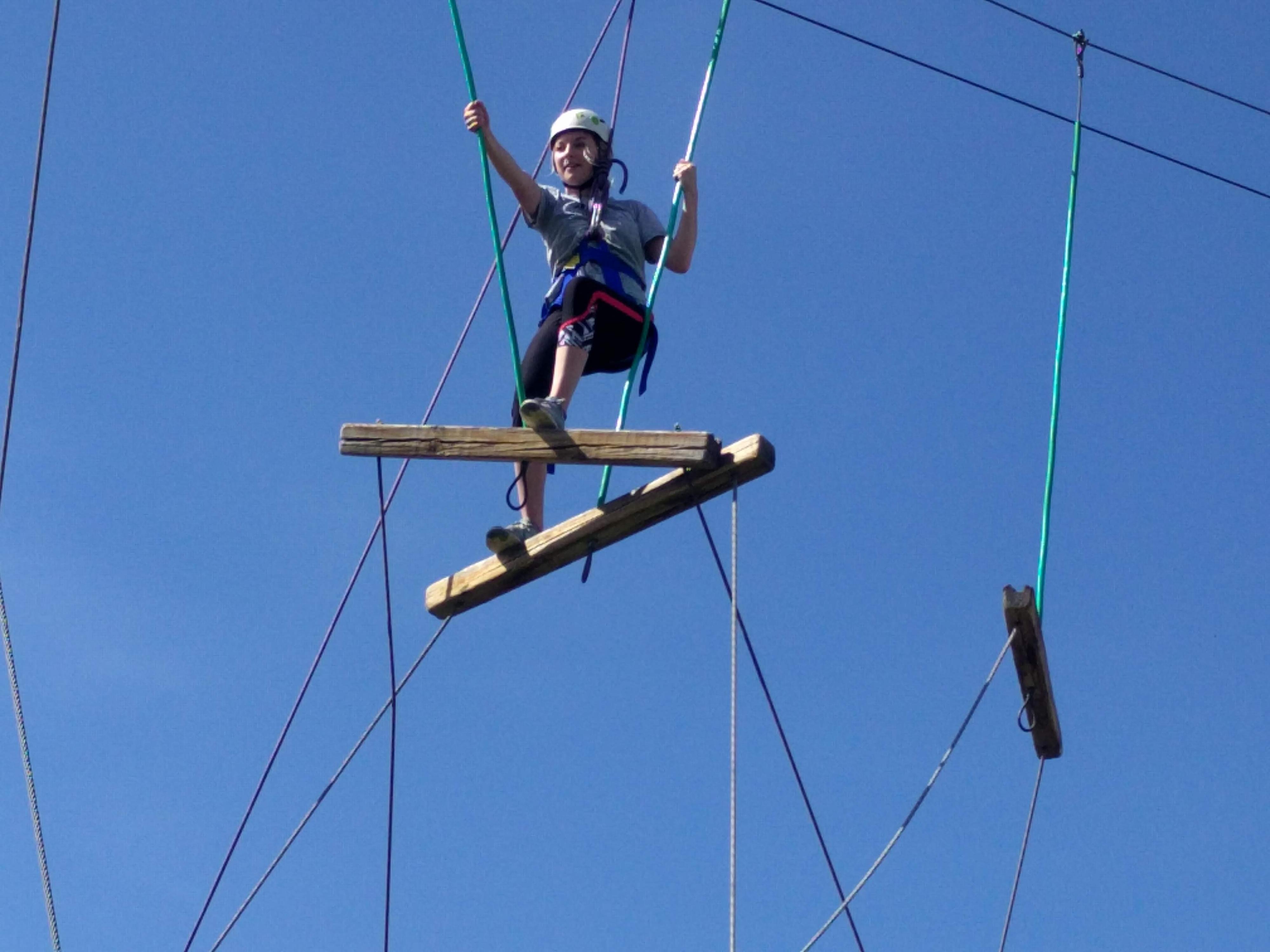 Person climbing through ropes challenge course