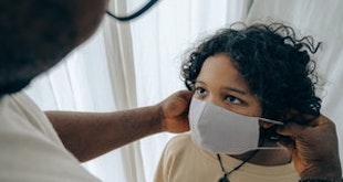 Parent putting mask on child