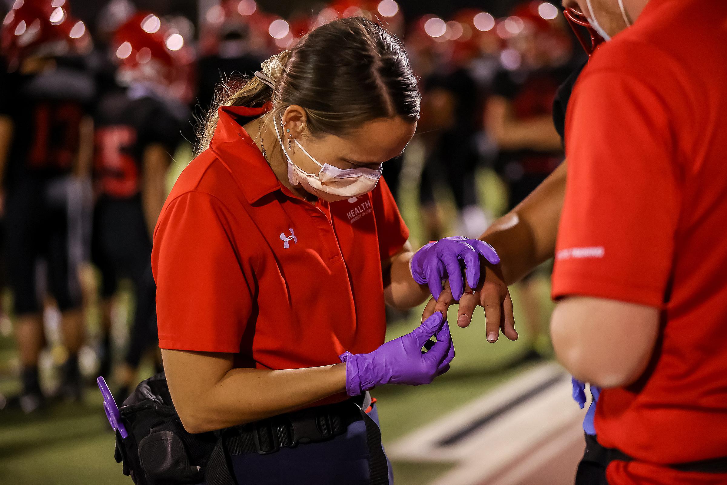 Athletic Trainer Jenny cleaning an athlet's injury at a game