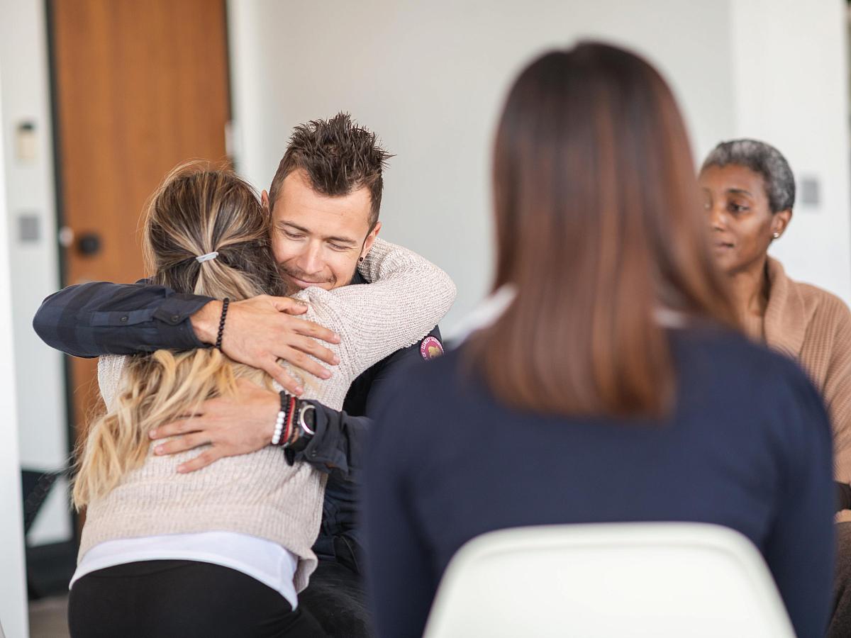 Man and women hug during group therapy