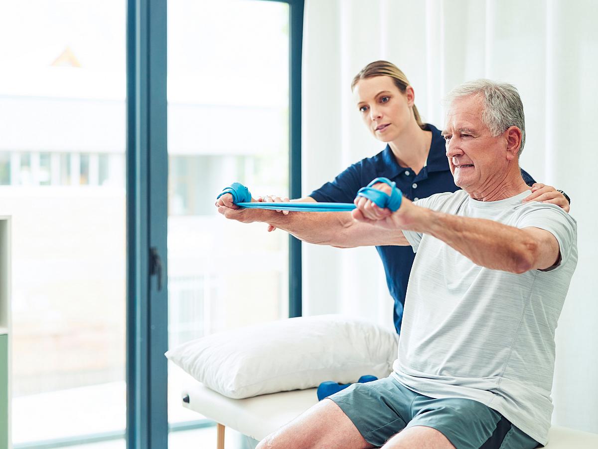 Older man using stretch bands in physical therapy