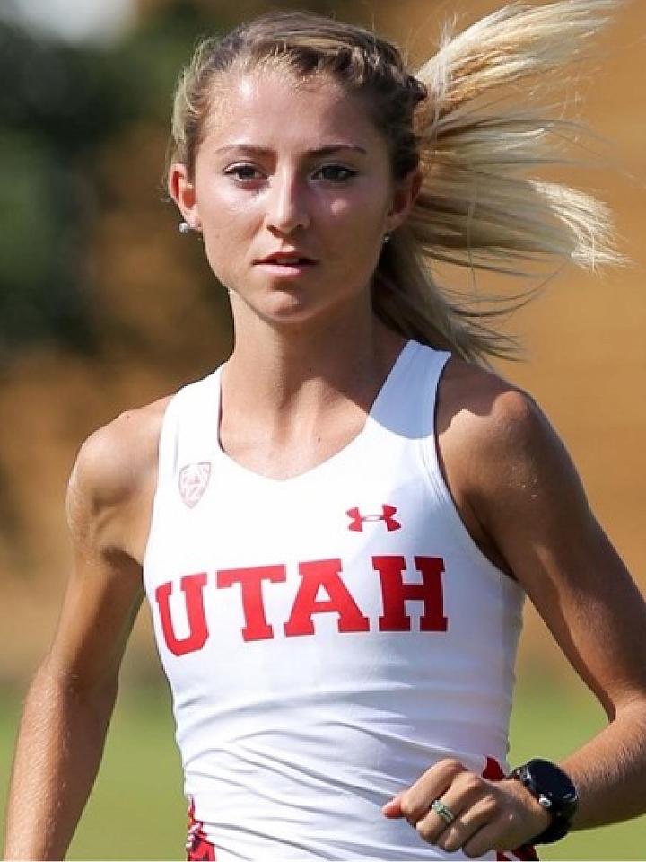 Blonde woman running in white tank top that says "Utah" in red.