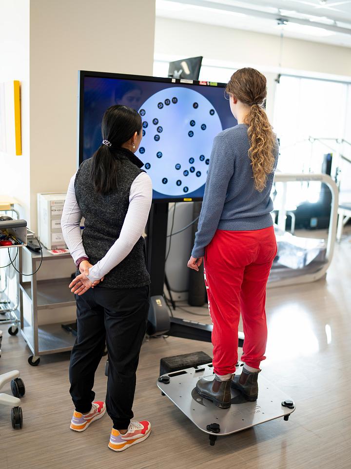 A female U of U Health provider oversees a female patient using an interactive touch screen