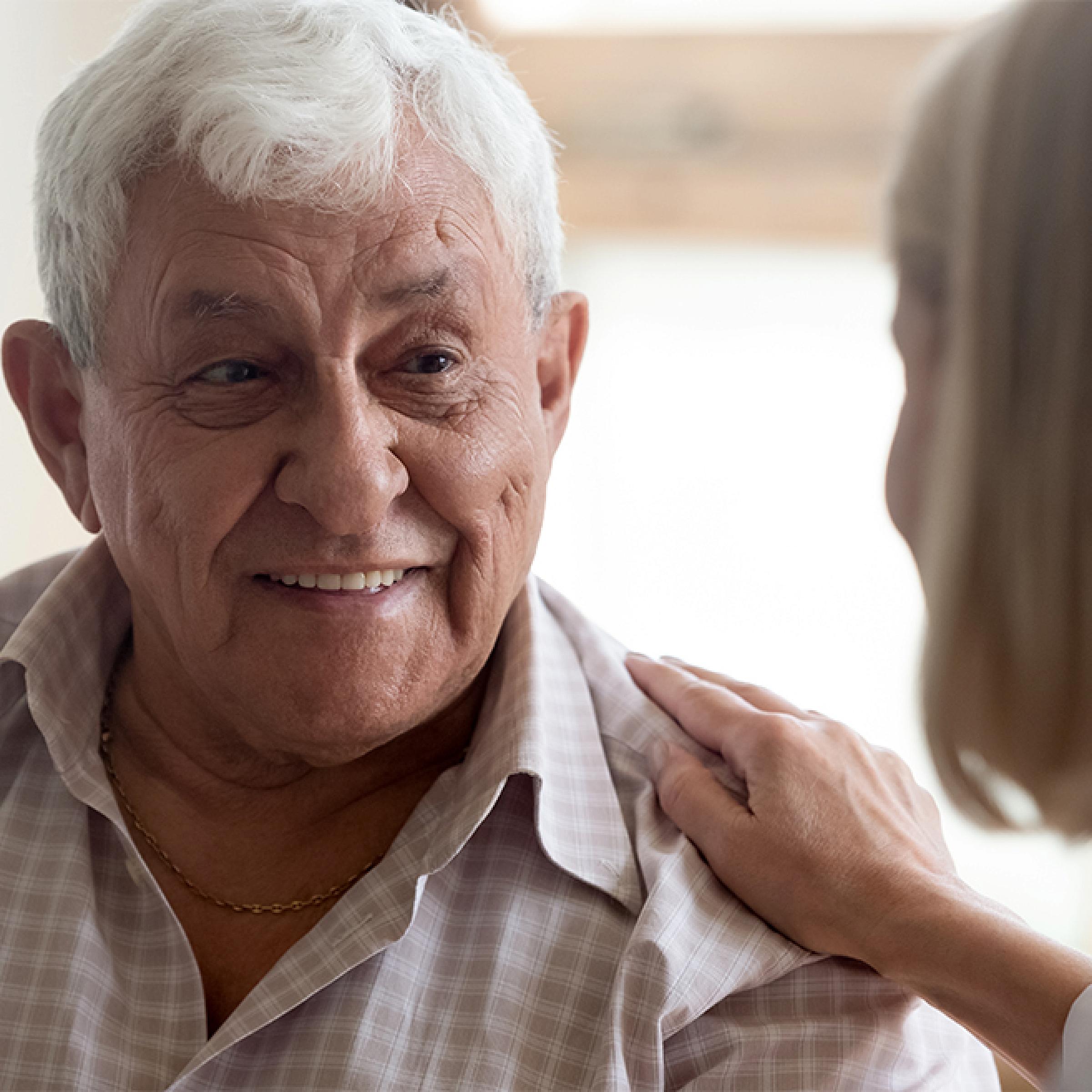 Older woman putting her hand on shoulder of older man