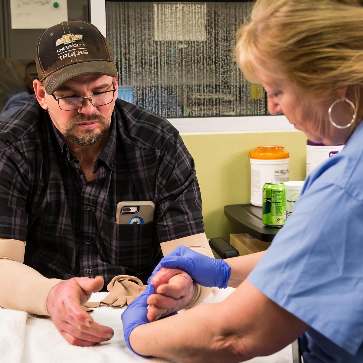 Burn patient getting burn therapy on his hands and arms by a burn therapist at U of U Health Burn Center