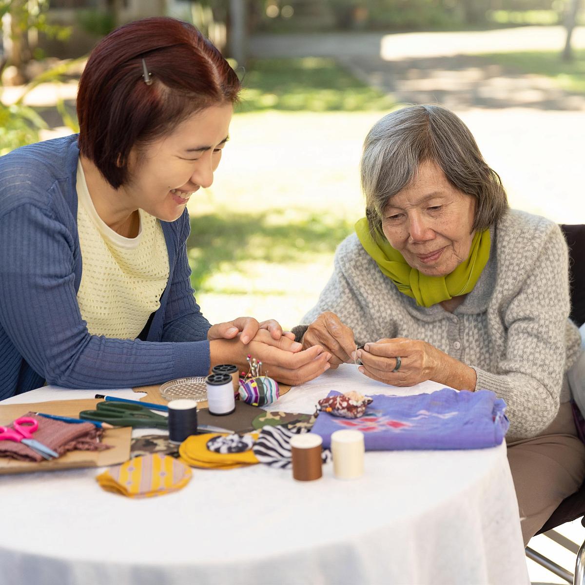 Picture of elderly Asian woman in a wheelchair doing arts and crafts outside