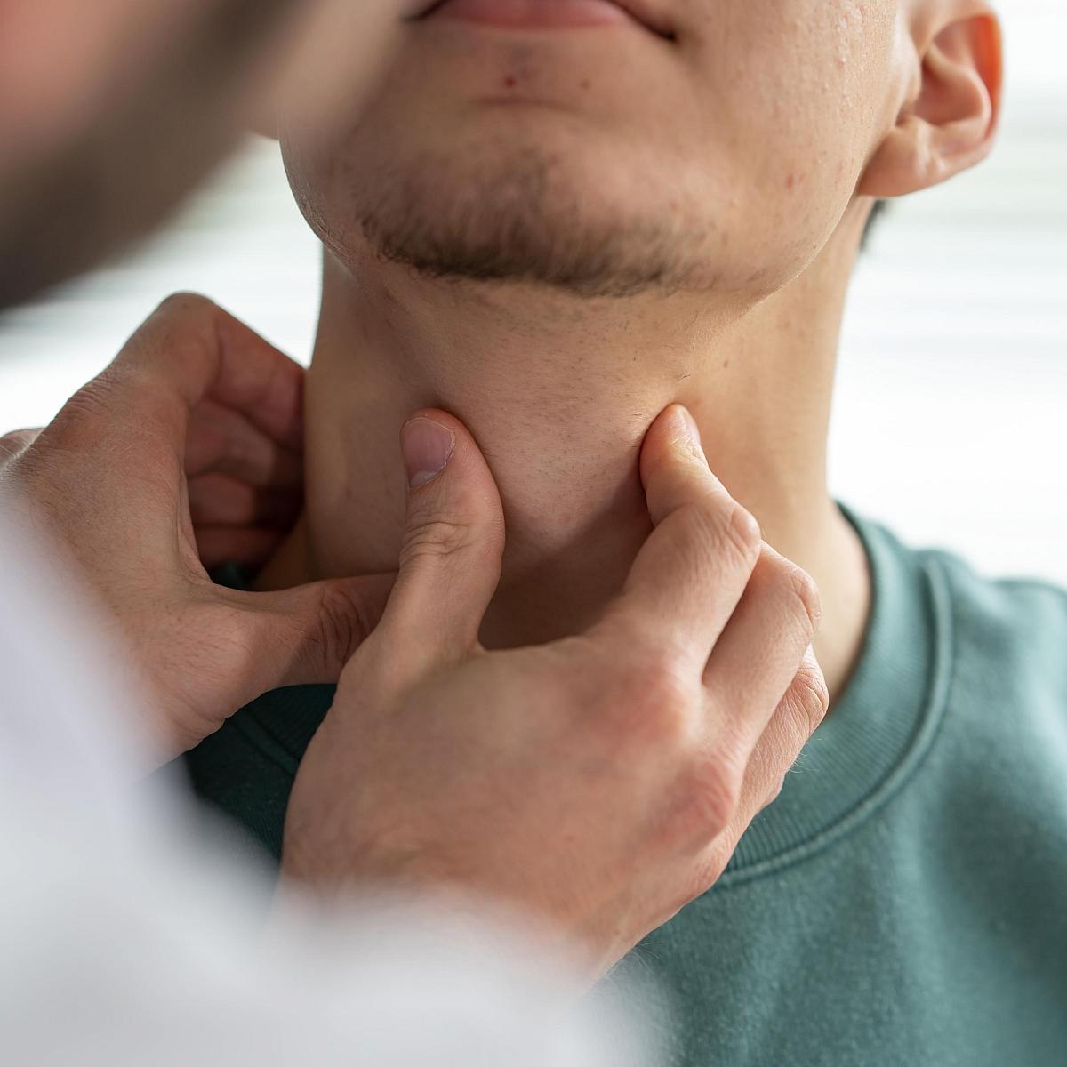 Picture of white male doctor examining the front of white male patient's throat
