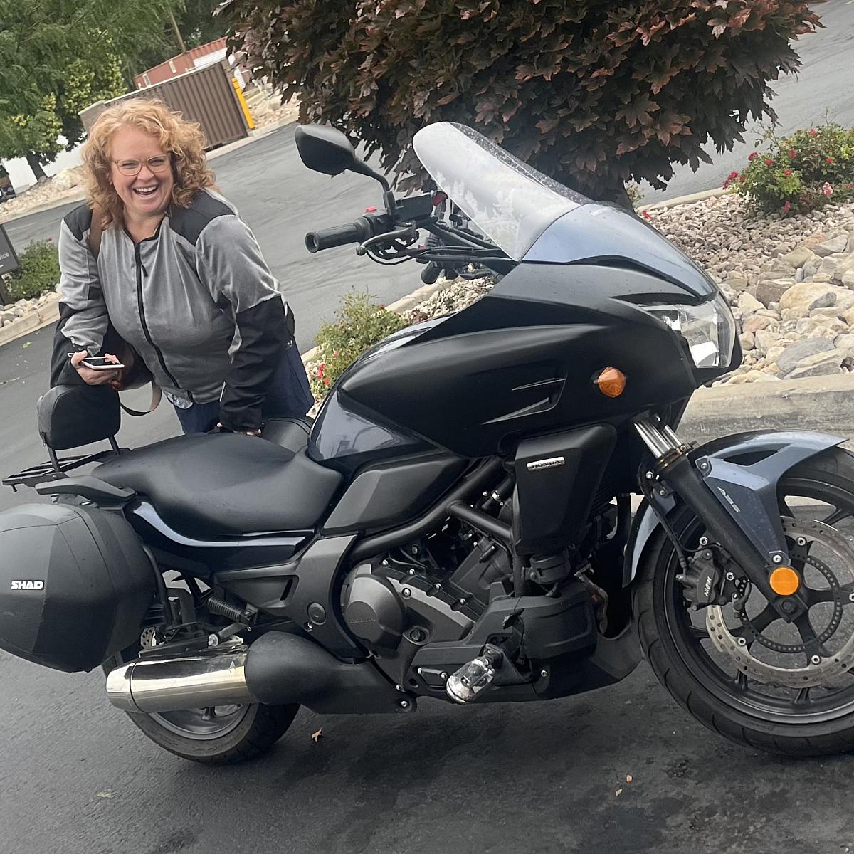 Mary Brickey stands behind her black motorcycle