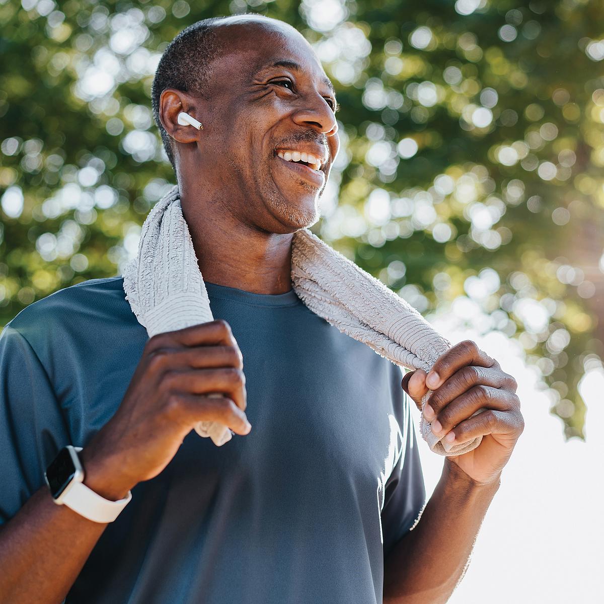 Smiling man with towel around his neck after exercising