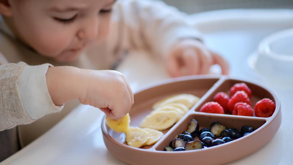 Young child eating fruit in a high chair