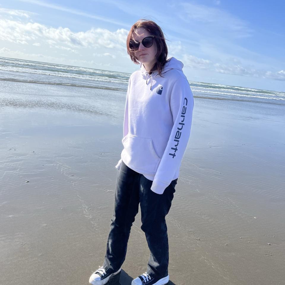 Sammy, a Teenscope program participant standing on the beach in a hoodie and black pants